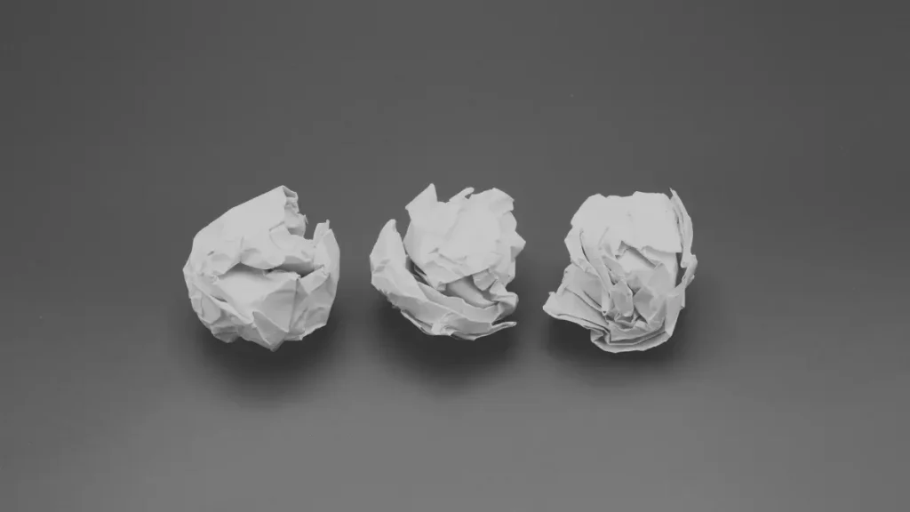 Three crumpled paper balls on a plain background, symbolising brainstorming and developing new learning ideas.
