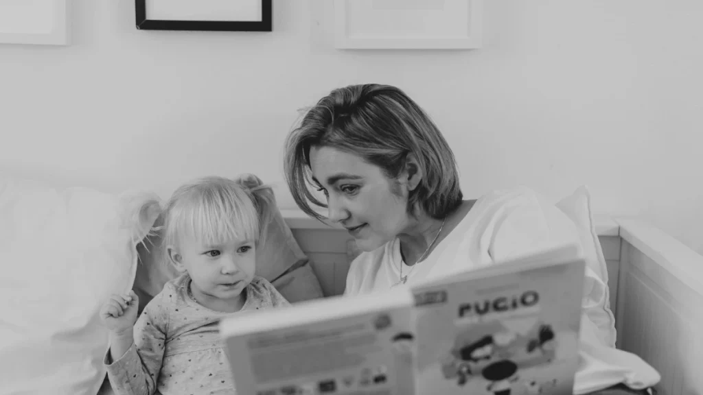 Parent reading a book with a young child at home, representing shared learning and confidence-building in home education.