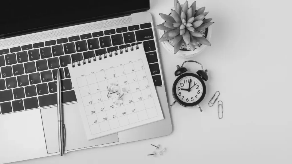 Calendar, laptop and notebook used for planning a flexible home education schedule.