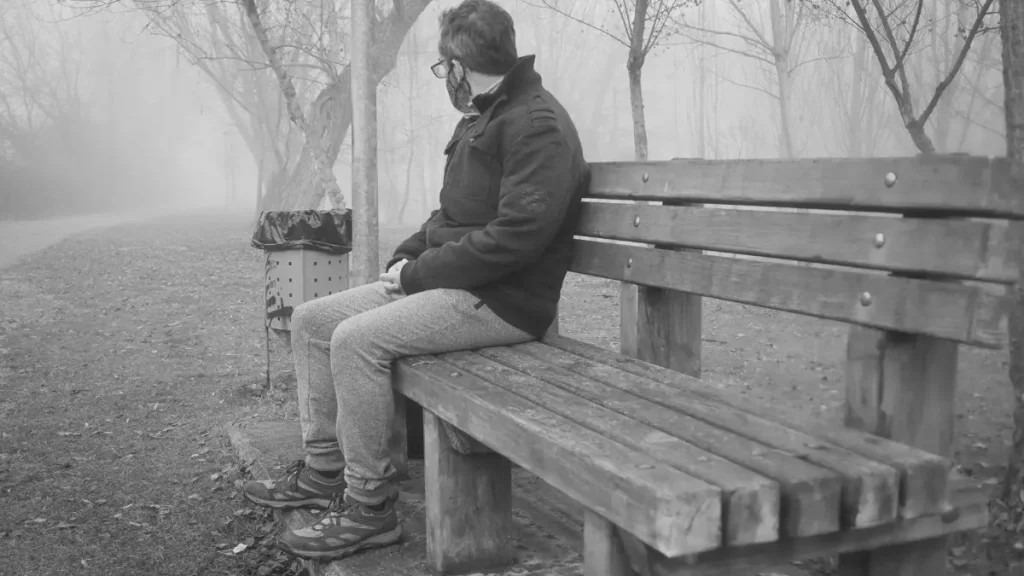 Person sitting alone on a park bench in fog, representing the home education socialisation myth.
