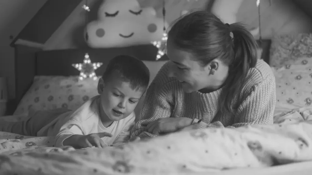 Parent reading with a young child in bed as part of a gentle home education routine.