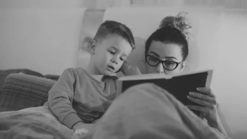Parent and child reading together in a cosy bedroom, showing everyday learning in home education.