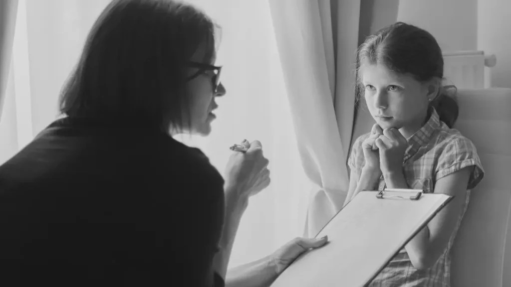 Adult speaking gently with a worried-looking child, representing emotional distress, school-related anxiety, and the need for support.