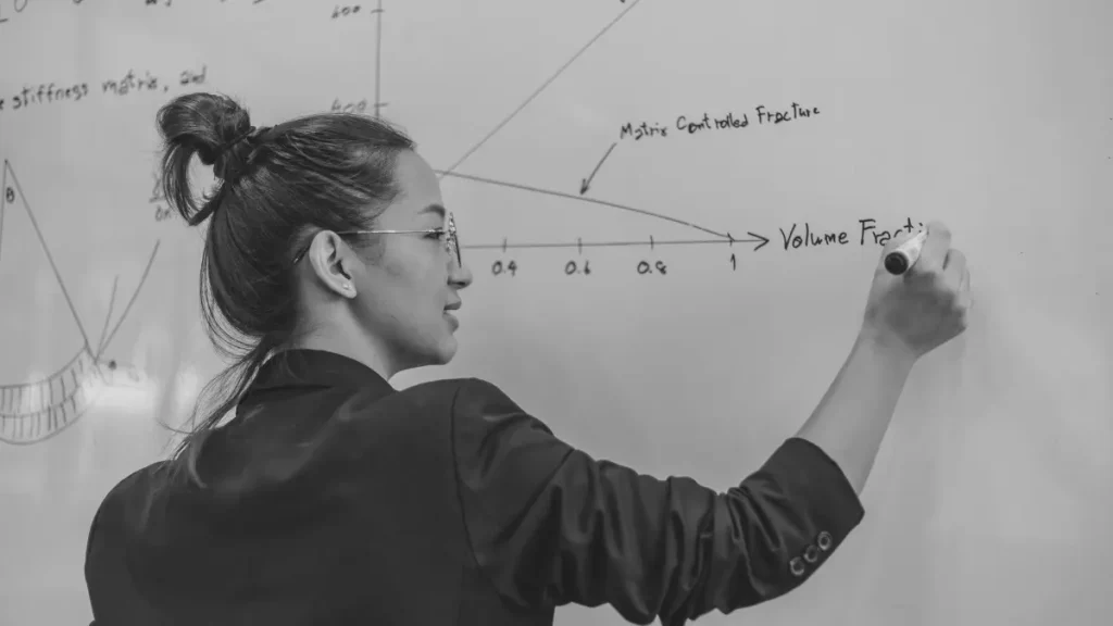 Teacher writing diagrams and notes on a whiteboard, representing the misconception that home education has to look like traditional school.