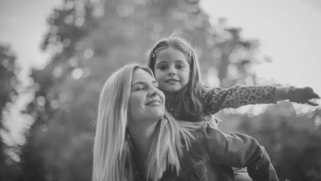 Parent carrying a young child outdoors, representing trust, confidence, and relationship-based learning in home education.