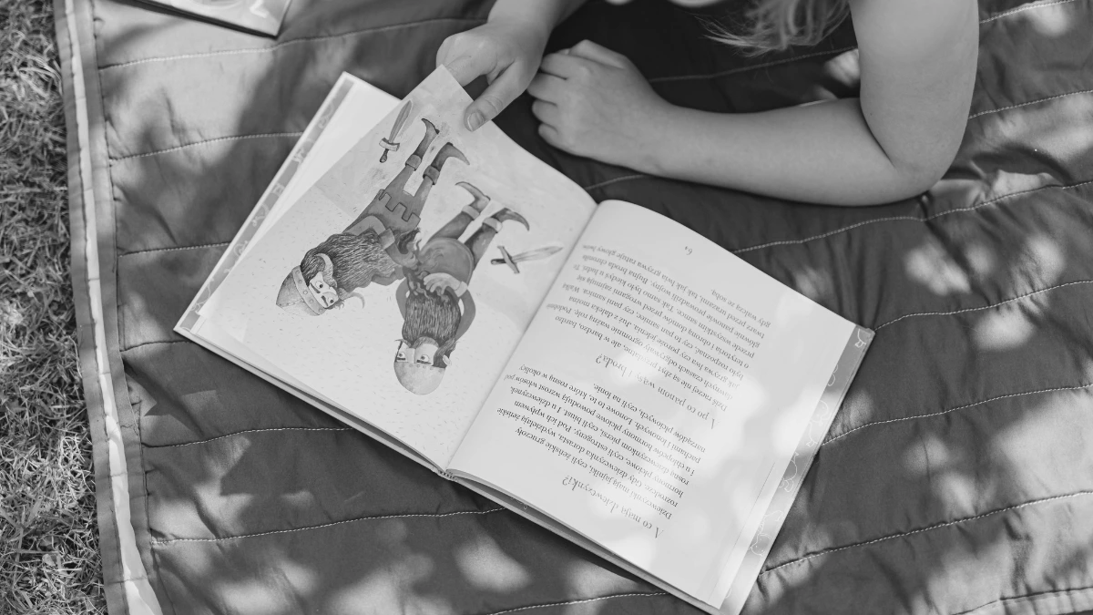 Open children’s book on a picnic blanket outdoors, representing flexible learning through books in home education.