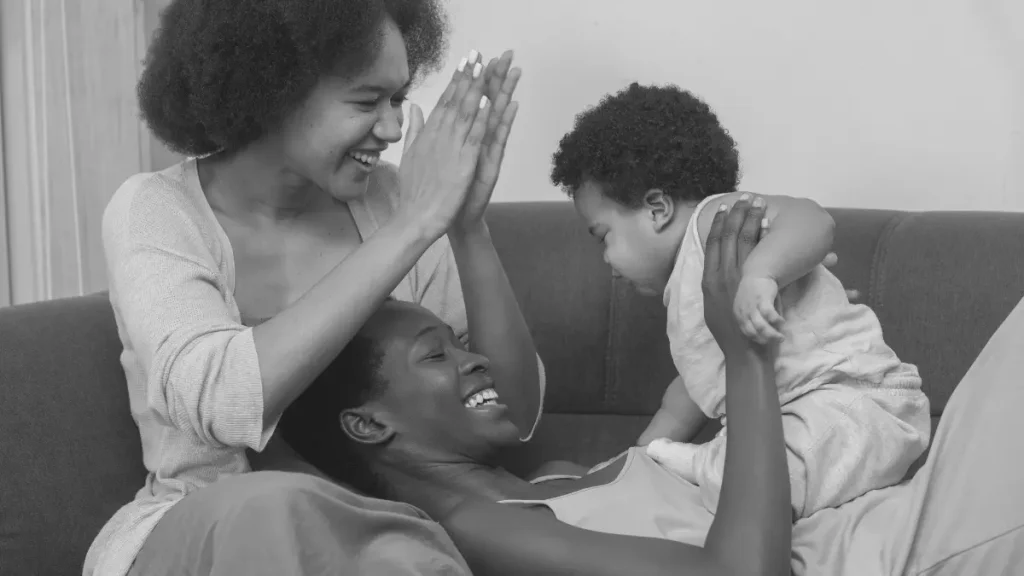 Two parents and a young child laughing together on a sofa, representing connection, joy, and emotional security in family life.