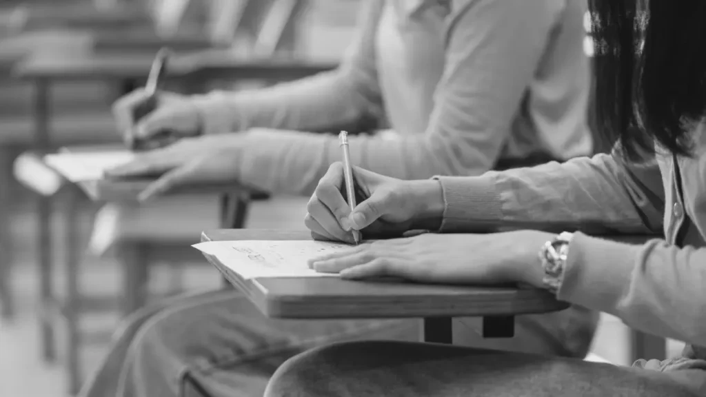 Students writing in exercise books at classroom desks, representing the myth that home educated children can’t take exams or gain qualifications.