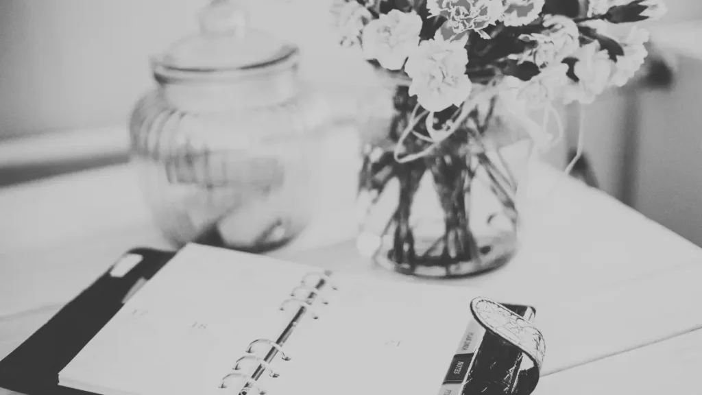 Open planner on a table beside flowers and a compass, representing personalised home education planning.
